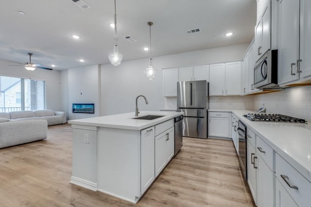 kitchen with visible vents, light wood-style flooring, a sink, appliances with stainless steel finishes, and tasteful backsplash