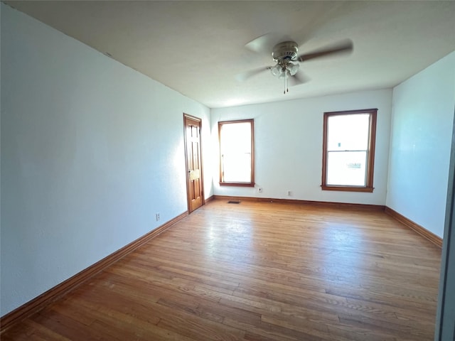 unfurnished room featuring visible vents, baseboards, wood finished floors, and a ceiling fan