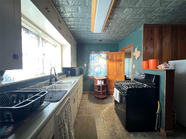 kitchen featuring a sink, decorative light fixtures, baseboards, and black appliances