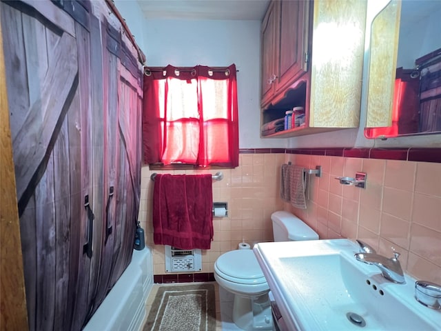 full bath with tile patterned floors, a wainscoted wall, shower / bath combo with shower curtain, toilet, and a sink