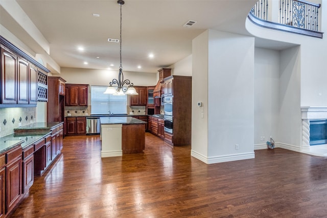 kitchen featuring backsplash, stainless steel appliances, a kitchen island, and dark wood finished floors