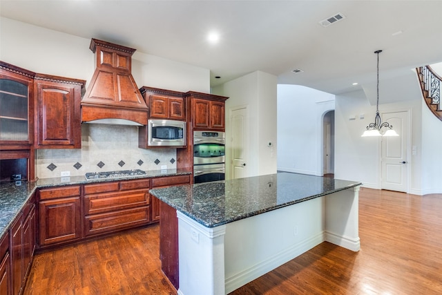 kitchen with visible vents, arched walkways, appliances with stainless steel finishes, custom exhaust hood, and dark wood-style flooring