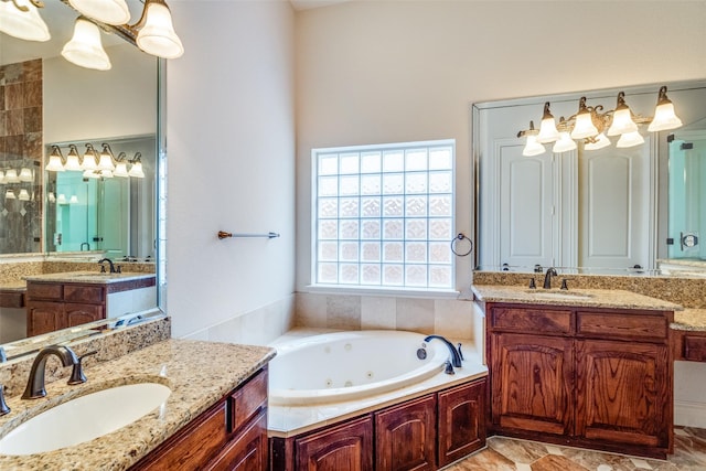 bathroom with a tub with jets, two vanities, and a sink