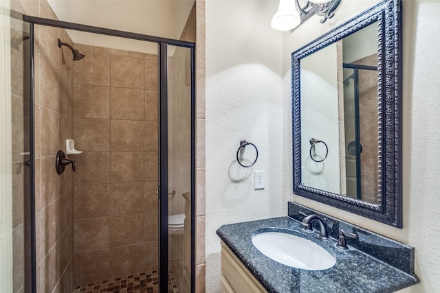 bathroom featuring a stall shower, vanity, and a textured wall