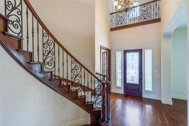 entryway featuring a notable chandelier, a high ceiling, baseboards, and wood finished floors