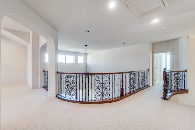 hallway featuring an upstairs landing, recessed lighting, arched walkways, and carpet