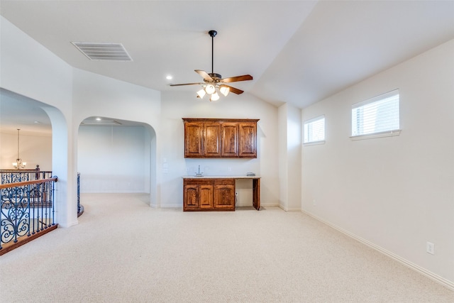 interior space featuring a ceiling fan, visible vents, baseboards, arched walkways, and light colored carpet