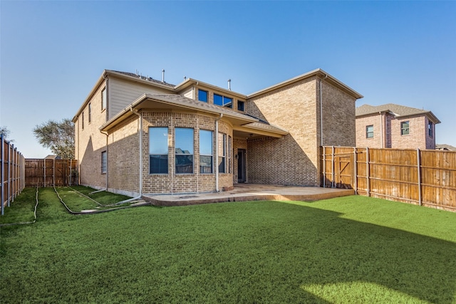 rear view of house featuring a yard, a patio, brick siding, and a fenced backyard