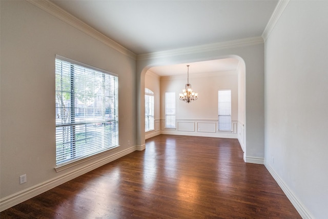 spare room featuring dark wood finished floors, arched walkways, an inviting chandelier, and ornamental molding