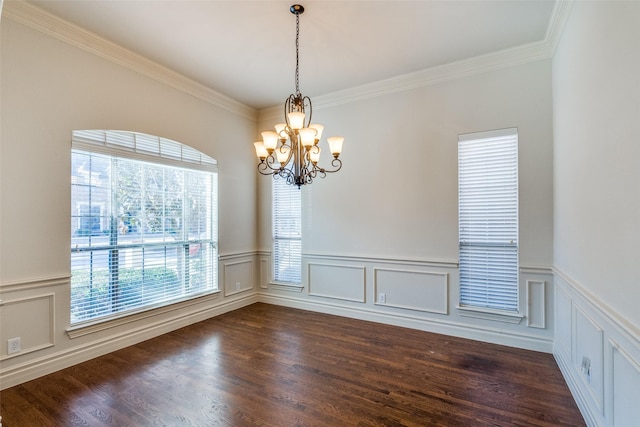 empty room featuring a chandelier, wainscoting, dark wood finished floors, and crown molding