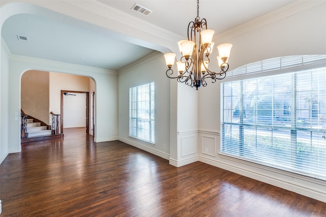 empty room with arched walkways, visible vents, dark wood finished floors, and stairway