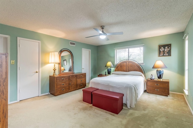 carpeted bedroom with a textured ceiling, baseboards, visible vents, and ceiling fan