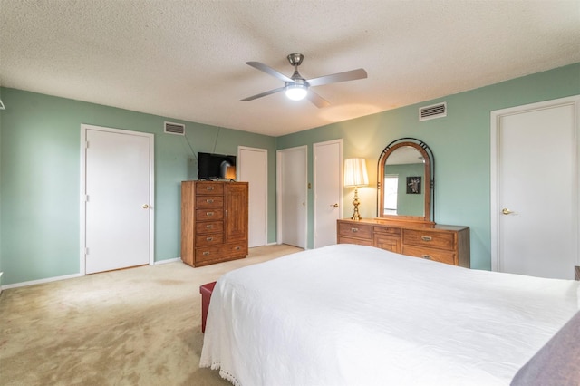 carpeted bedroom featuring ceiling fan, baseboards, visible vents, and a textured ceiling