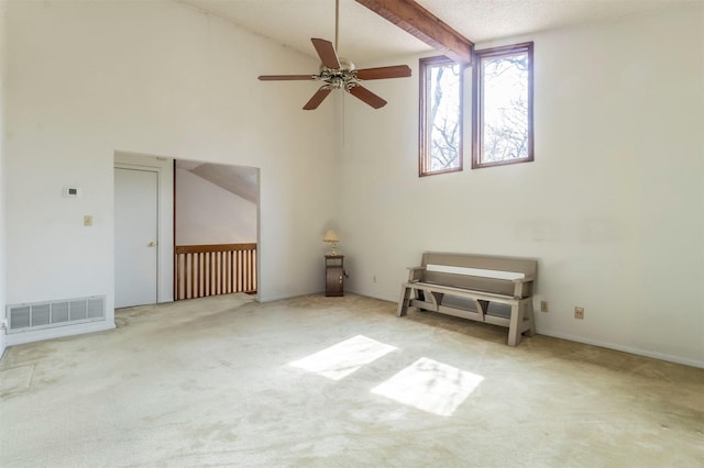 carpeted spare room featuring visible vents, beamed ceiling, a ceiling fan, and a towering ceiling