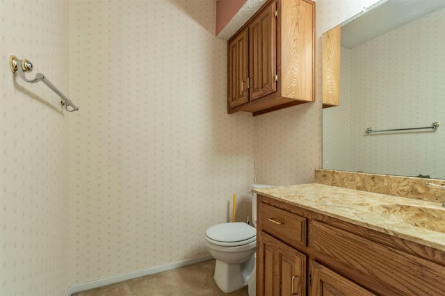 bathroom with wallpapered walls, toilet, vanity, and baseboards