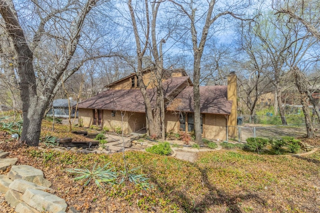 view of front of home with fence, brick siding, and a chimney