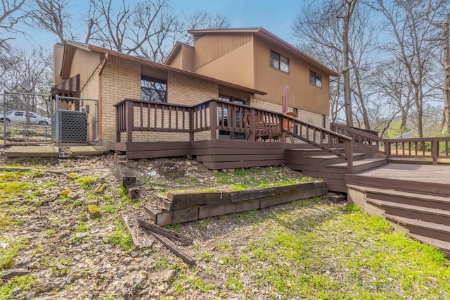 back of property featuring brick siding, a deck, and fence