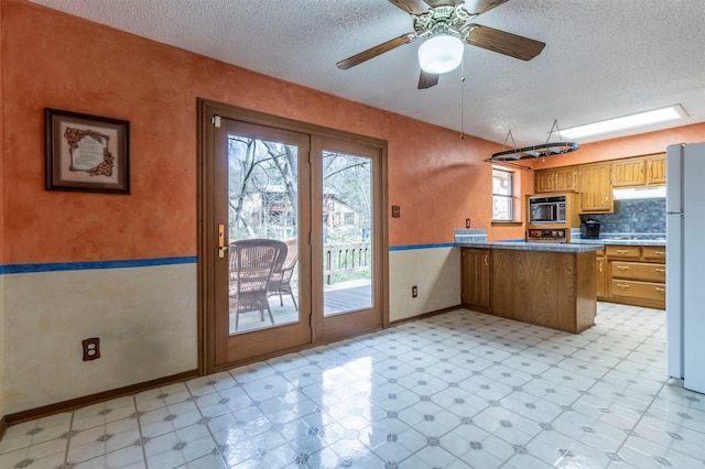 kitchen with built in microwave, light floors, a peninsula, and freestanding refrigerator