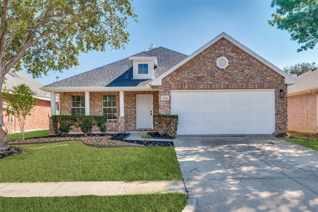 view of front of home featuring driveway, a shingled roof, a front lawn, a garage, and brick siding