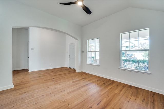 unfurnished room with light wood finished floors, ceiling fan, baseboards, lofted ceiling, and arched walkways