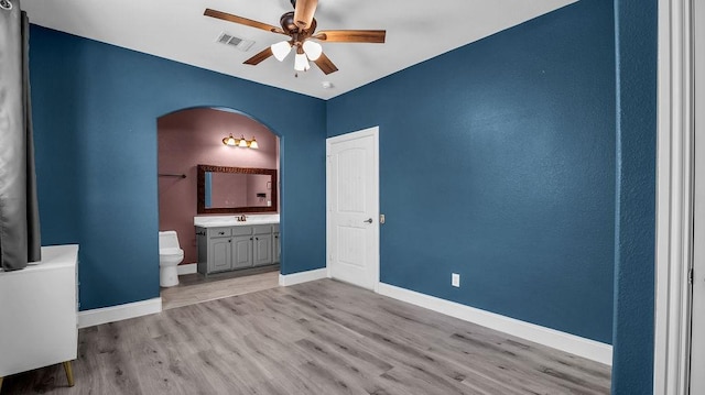 unfurnished bedroom featuring visible vents, baseboards, light wood-style floors, and ensuite bathroom