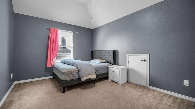 carpeted bedroom with a textured wall, baseboards, and vaulted ceiling