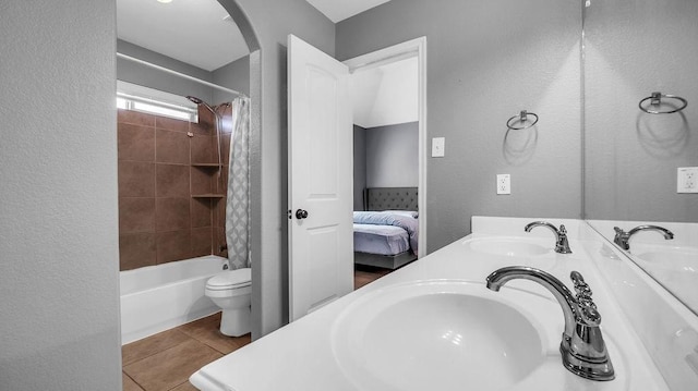 ensuite bathroom featuring a sink, toilet, and tile patterned flooring