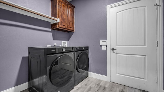 clothes washing area featuring baseboards, cabinet space, independent washer and dryer, and light wood-style flooring