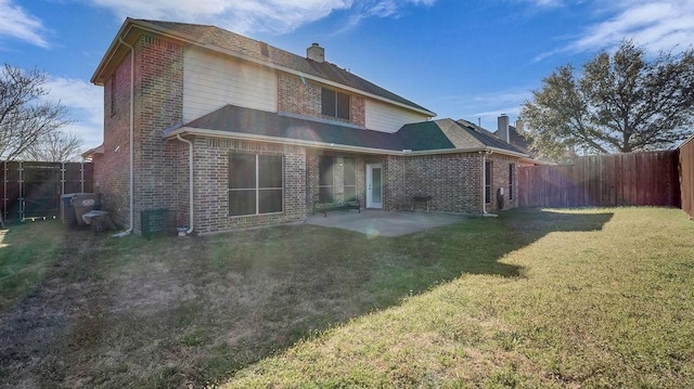 back of property featuring a lawn, a patio, a fenced backyard, brick siding, and a chimney