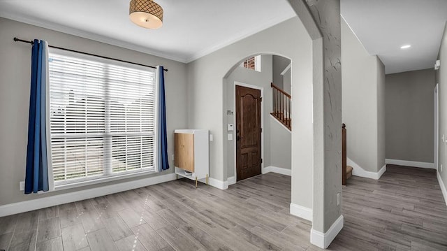 spare room featuring baseboards, arched walkways, a healthy amount of sunlight, and wood finished floors