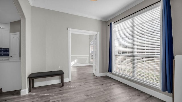 hall featuring baseboards, arched walkways, wood finished floors, and crown molding