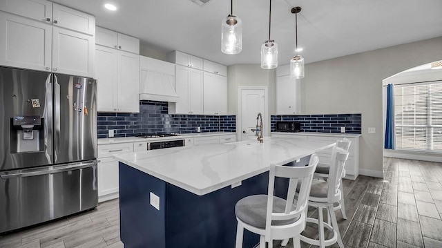 kitchen with premium range hood, wood tiled floor, stainless steel fridge with ice dispenser, decorative backsplash, and white cabinets