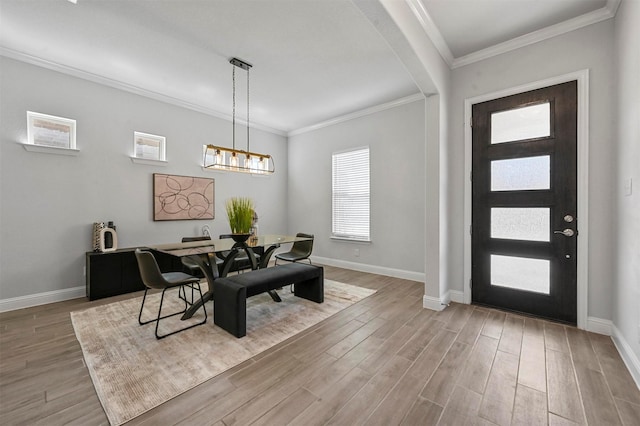 entryway with baseboards, arched walkways, light wood-style floors, crown molding, and a chandelier