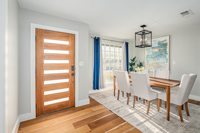 dining area featuring baseboards, visible vents, light wood finished floors, and a chandelier