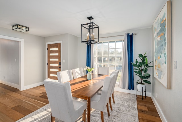 dining area featuring a chandelier, baseboards, and wood finished floors