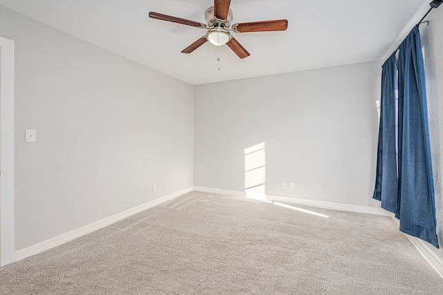 empty room with ceiling fan, baseboards, and light carpet