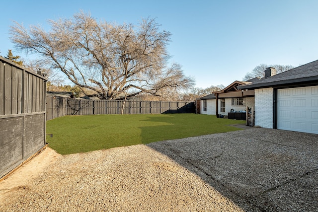 view of yard featuring a garage, gravel driveway, and fence