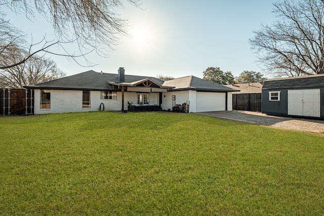 back of property with gravel driveway, fence, a lawn, an attached garage, and a storage unit