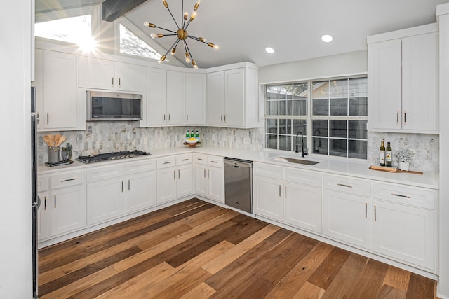 kitchen with vaulted ceiling with beams, a sink, light countertops, white cabinets, and appliances with stainless steel finishes