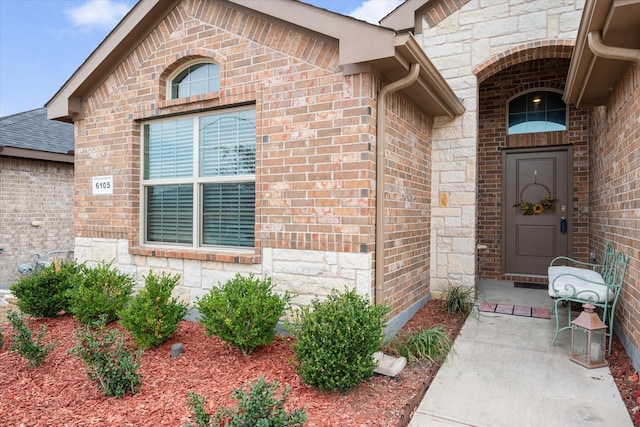 entrance to property featuring stone siding and brick siding