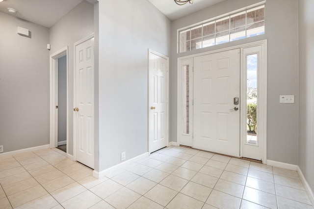 entryway with light tile patterned flooring and baseboards