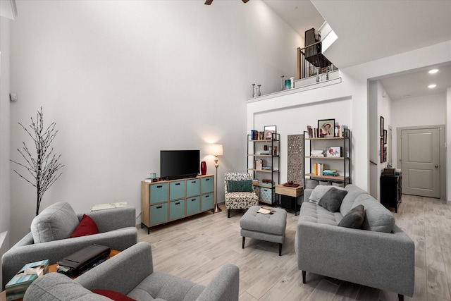 living room featuring recessed lighting, light wood-type flooring, a high ceiling, and ceiling fan