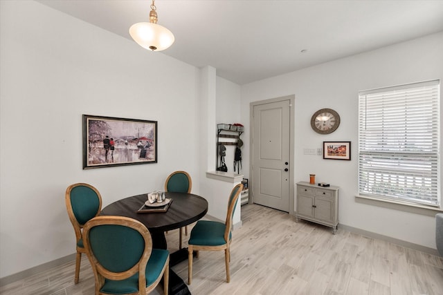 dining space featuring baseboards and light wood finished floors