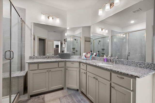 full bathroom featuring a sink, visible vents, a stall shower, and double vanity