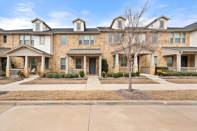 townhome / multi-family property featuring stone siding and covered porch