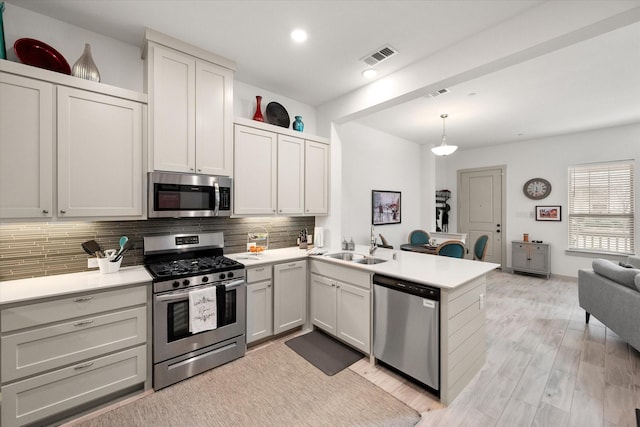 kitchen with visible vents, tasteful backsplash, stainless steel appliances, a peninsula, and light countertops