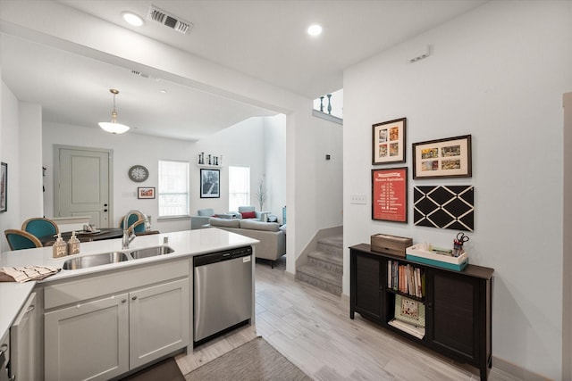 kitchen featuring visible vents, light wood-type flooring, a sink, light countertops, and dishwasher