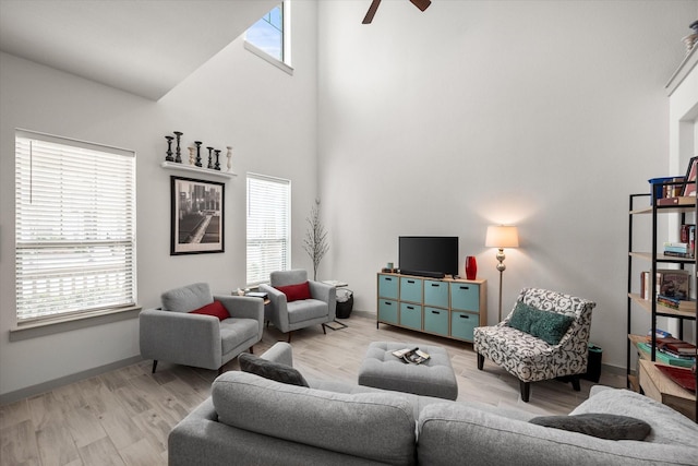 living area featuring a wealth of natural light, light wood-style floors, and a towering ceiling