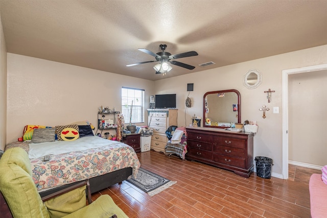 bedroom featuring visible vents, a textured ceiling, and wood finished floors