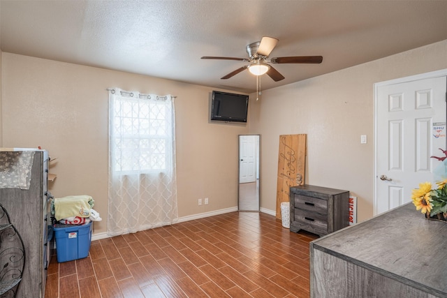 interior space featuring dark wood finished floors, a ceiling fan, baseboards, and a textured ceiling